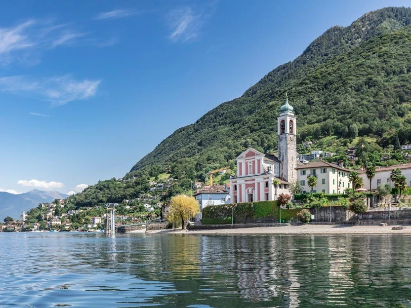 Il borgo di Vira Gambarogno sul Lago Maggiore con la chiesa rosa e le montagne